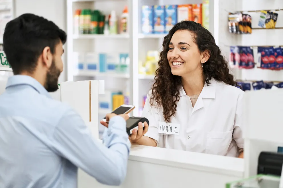 Man paying through smart phone at pharmacy checkout counter