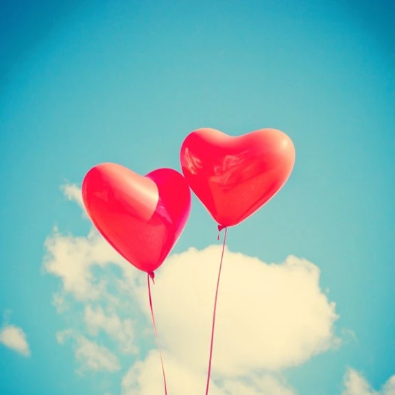 Two floating heart balloons in the sky