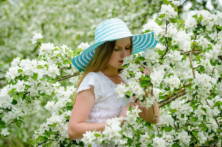Woman with hat smelling flowers