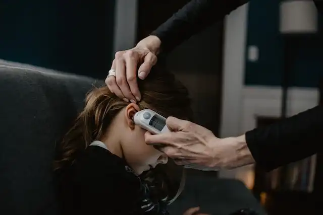 Adult taking a girl's temperature