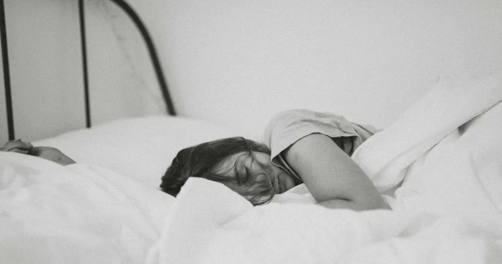 Black and white image of woman sleeping in bed