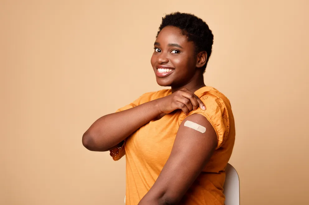 Black woman showing bandage on arm after vaccine