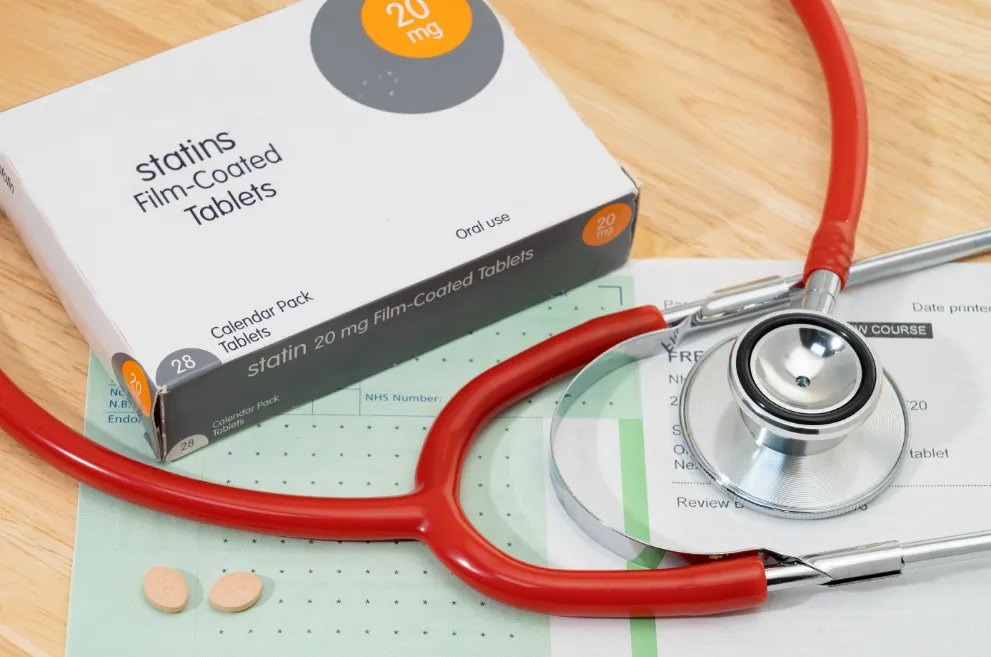 Box of statins with papers and stethoscope
