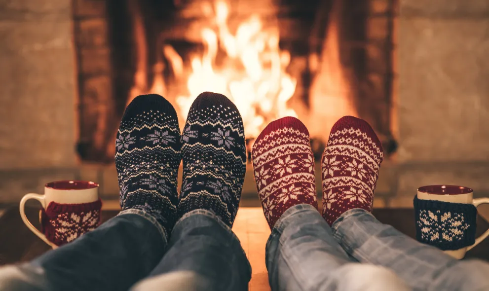 Couple in christmas socks relaxing in front of fireplace