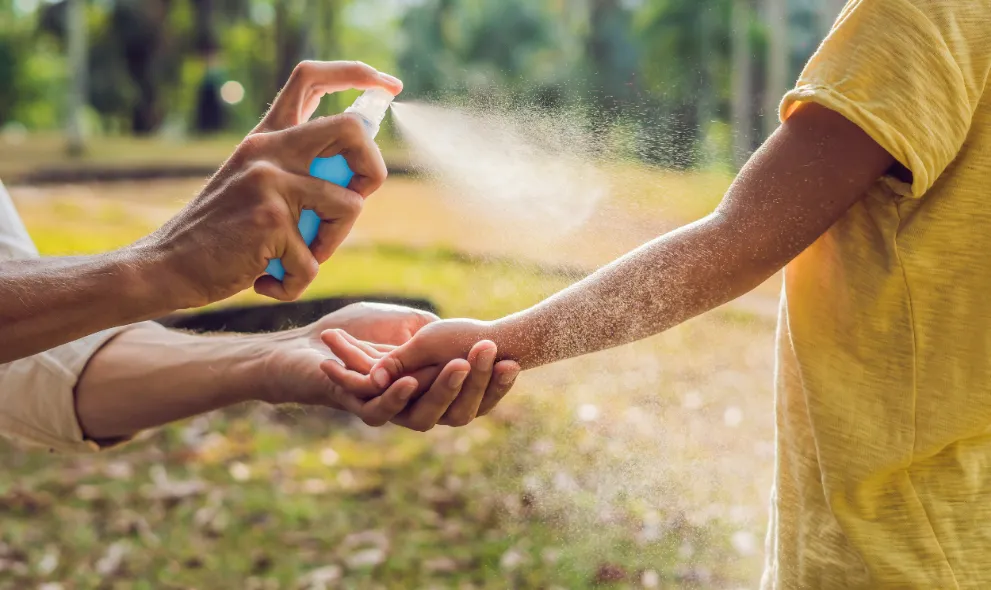 Dad spraying son with mosquito spray