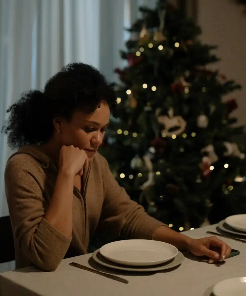 Woman looking sad with a Christmas tree in the background