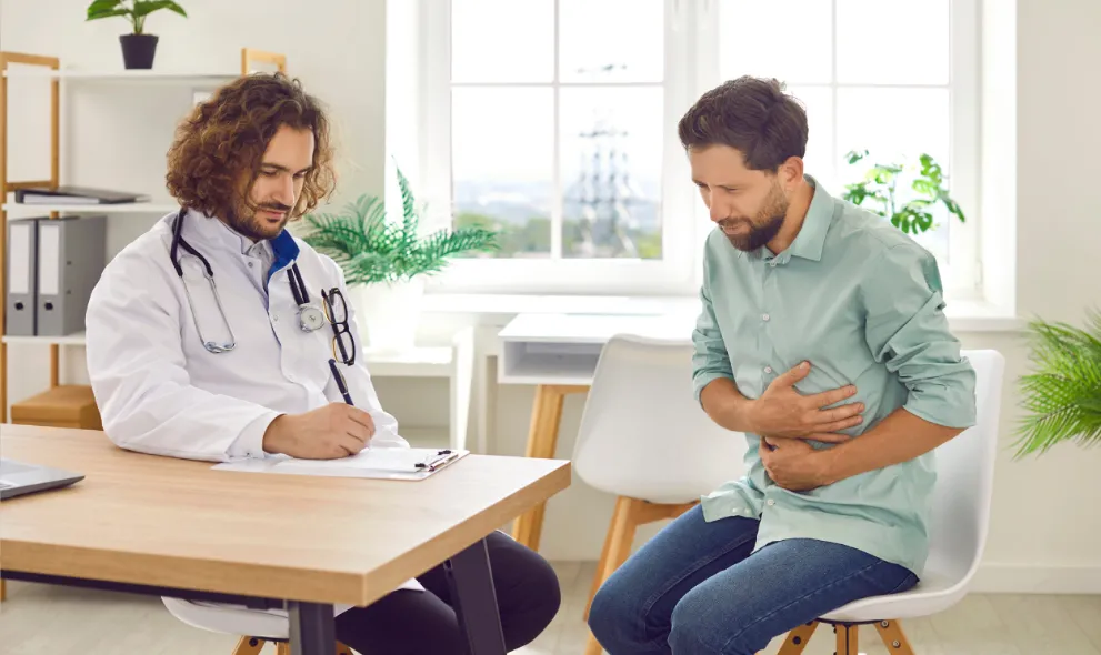 Doctor consulting male patient suffering with stomach pain