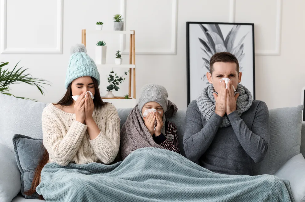 Family on sofa blowing noses