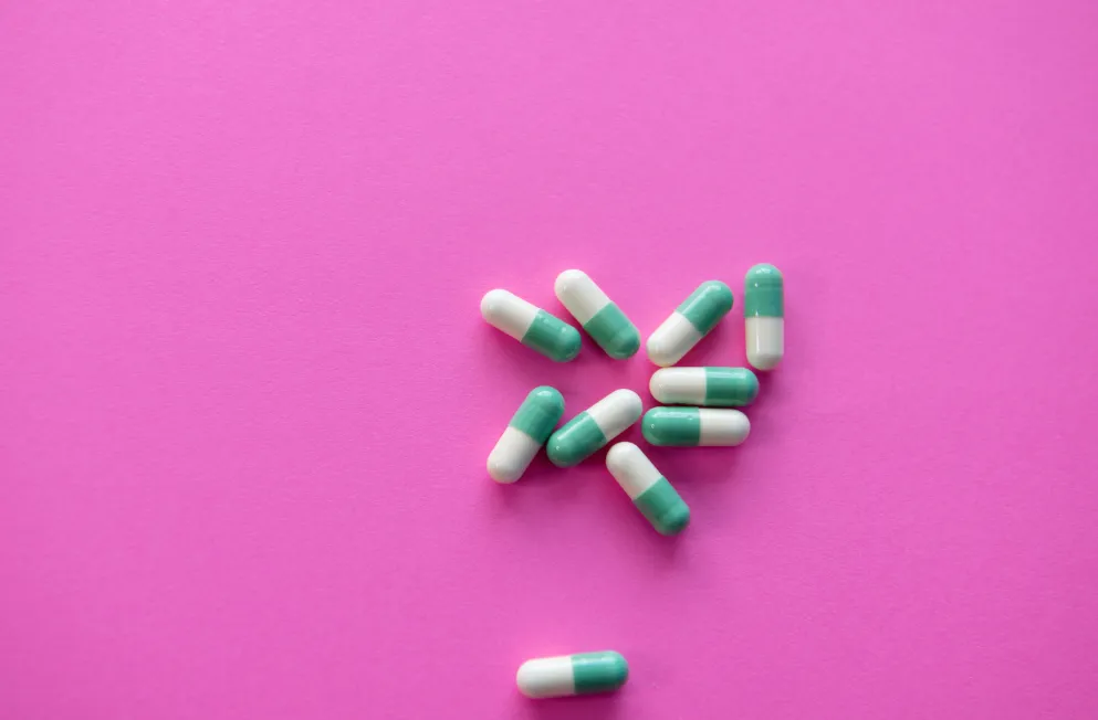 Green and white pills on pink background