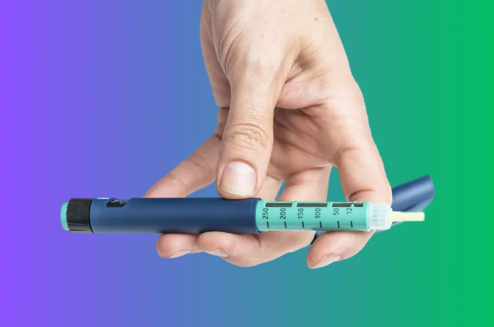 Hand holding diabetes injector pen on colored background