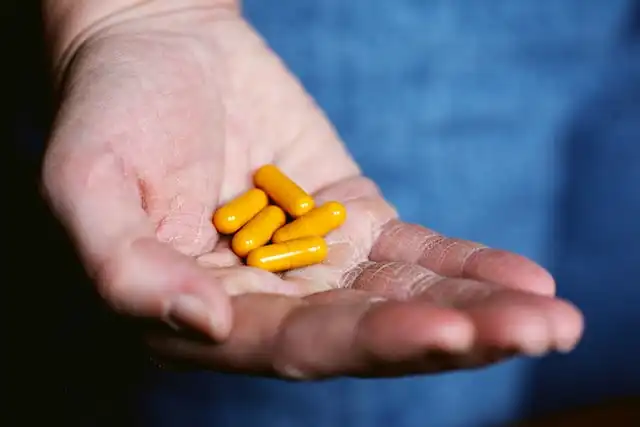 Hand holding five yellow capsules
