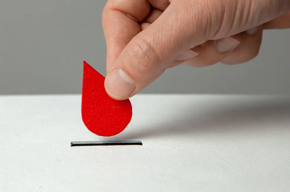 Hand placing paper blood drop into slot