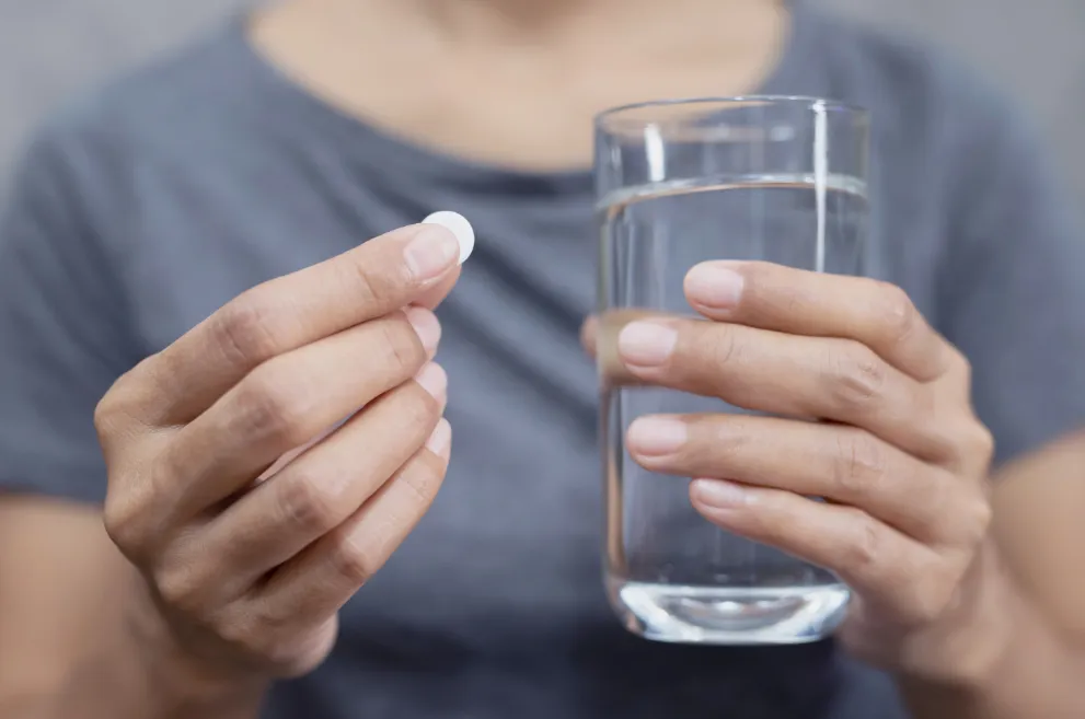 Hands holding pill and glass of water