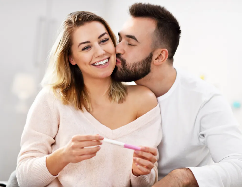 Happy couple holding positive pregnancy test