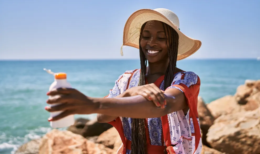 Happy woman applying sunscreen at the beach