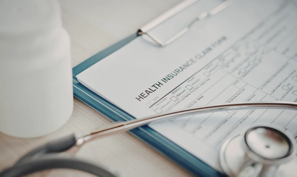 Health insurance form with stethoscope and bottle of pills