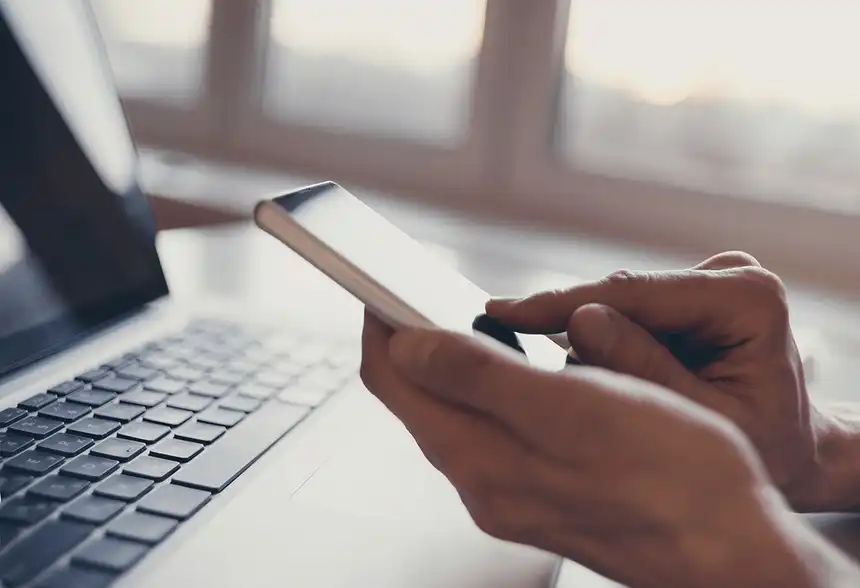 Person using phone in front of computer