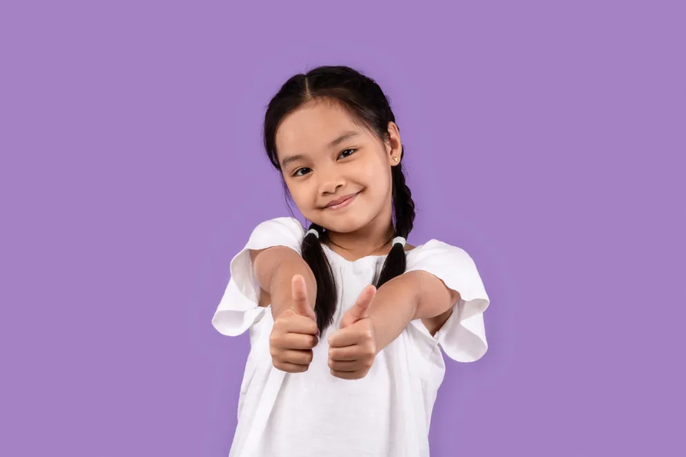 Little girl giving two thumbs up on purple background