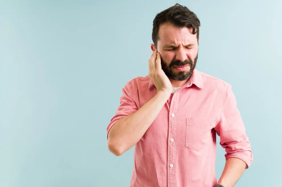 Man holding ear looking uncomfortable