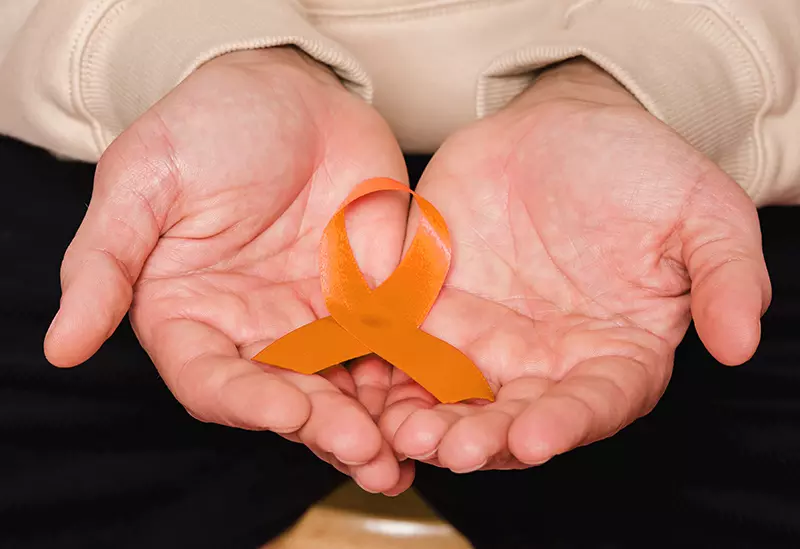 Man holding small orange ribbon