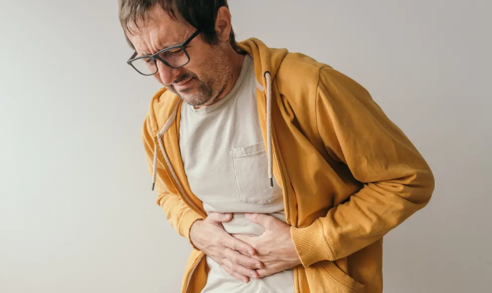 Man pressing lower left abdomen with painful grimace