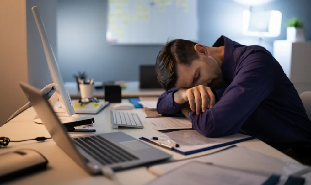 Man sleeping at desk during the day