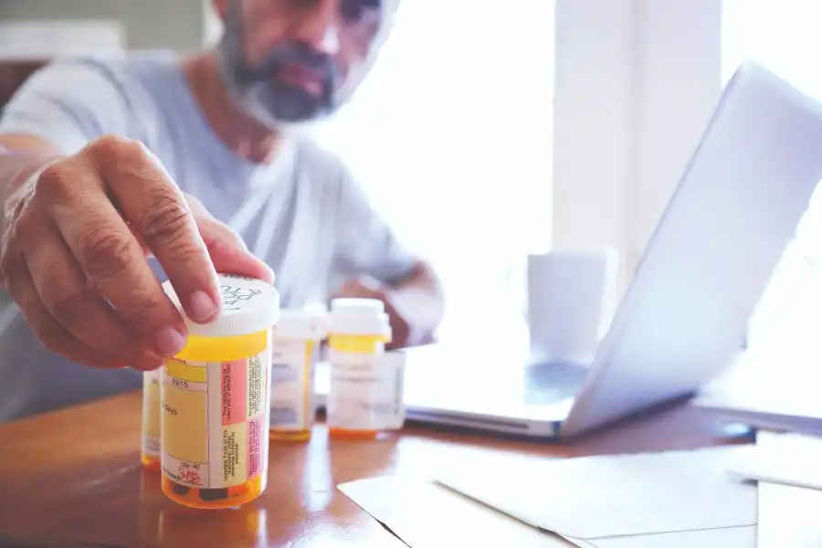 Man Viewing Prescription Bottles with Laptop