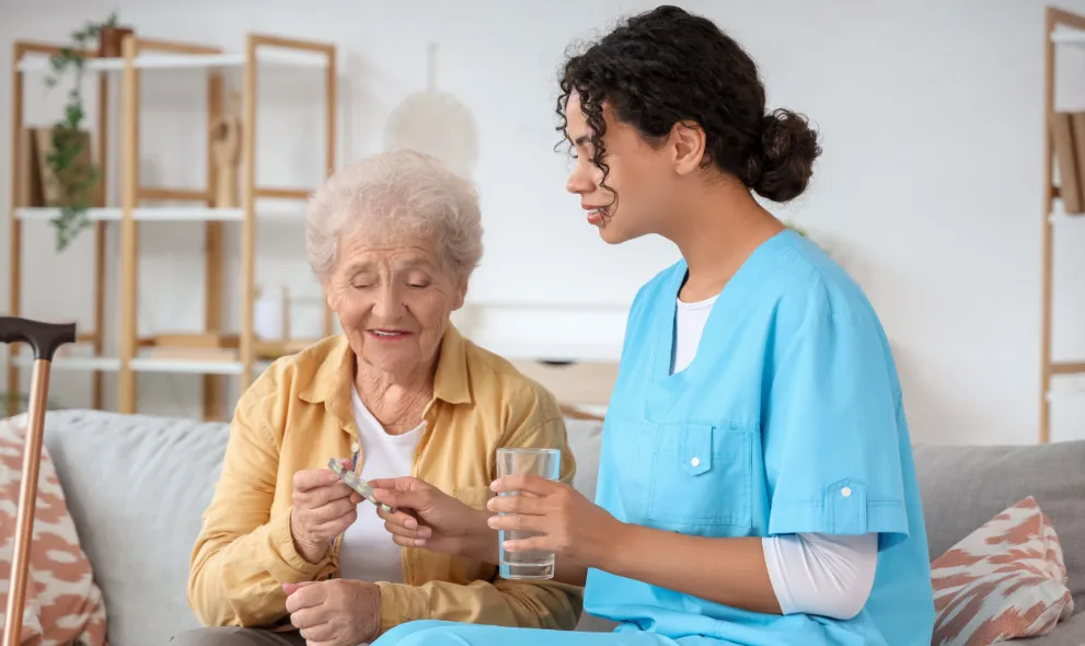 Medical worker giving eldery woman pills and glass of water