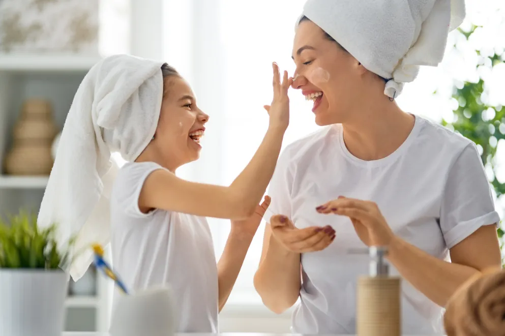 Mother and daughter applying moisturizer together