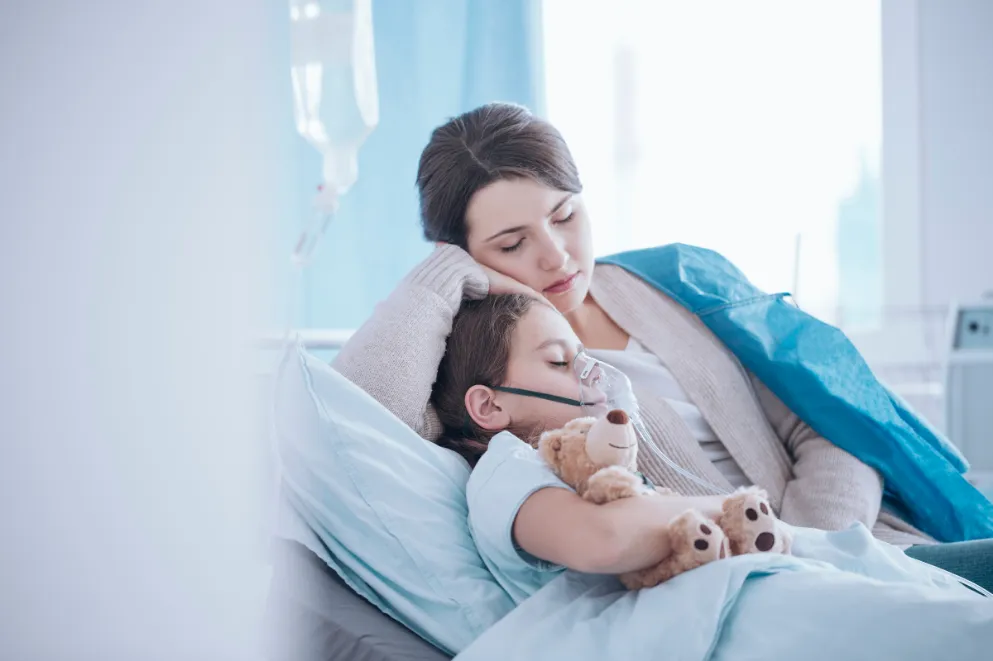 Mother in Hospital Bed with Child Holding Teddy Bear and Wearing Oxygen Mask