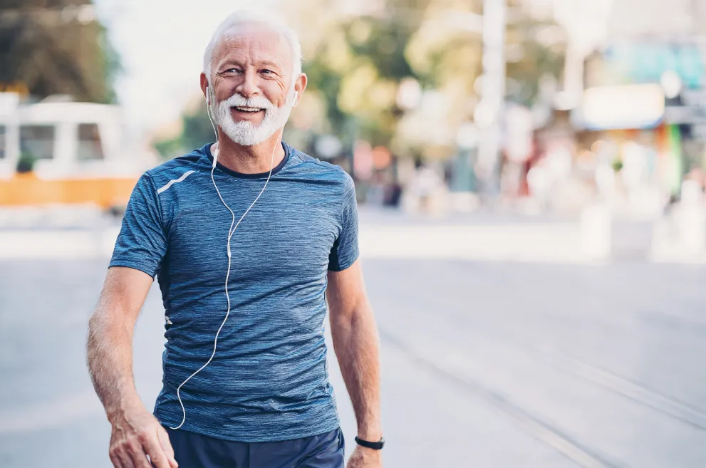 Older man exercising outdoors and wearing earbuds