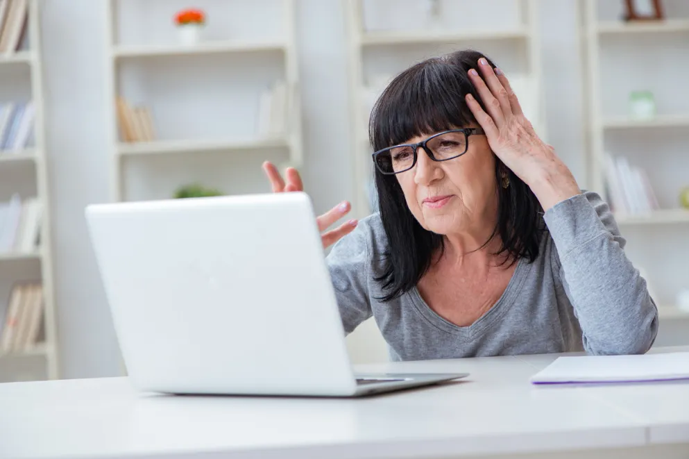 Older woman using laptop and looking confused