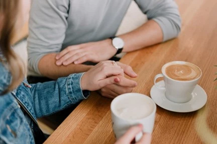 People holding hands over coffee