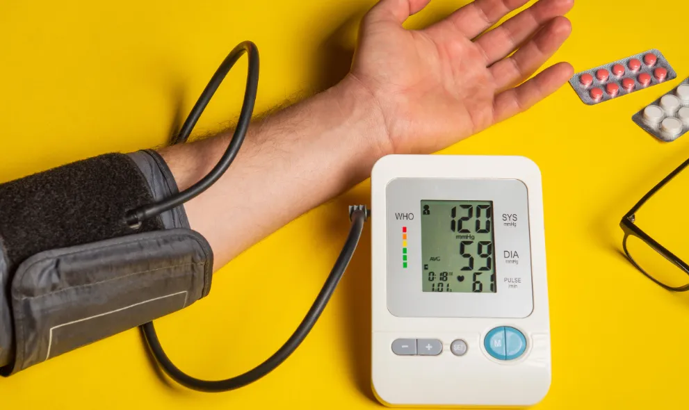 Person measuring their own blood pressure on yellow background