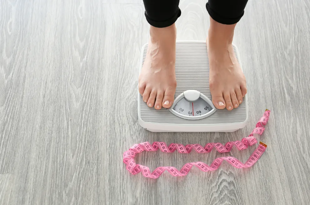 Person standing on scale with measuring tape on floor