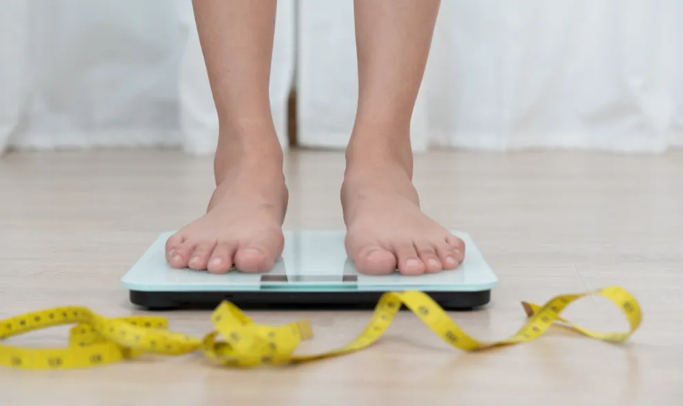 Person standing on scales with tape measure