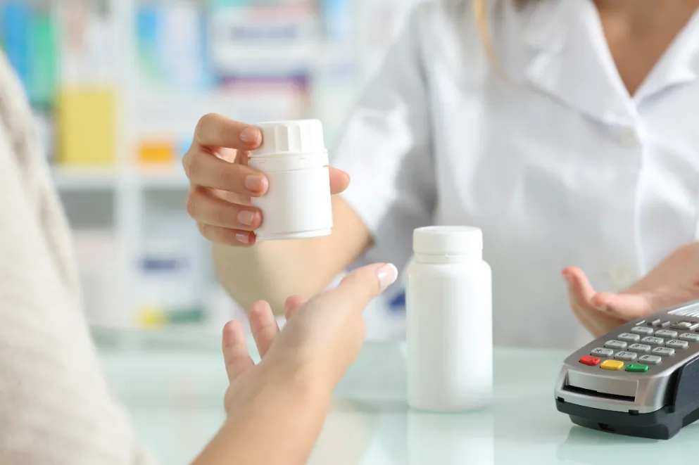 Pharmacist handing medication to customer