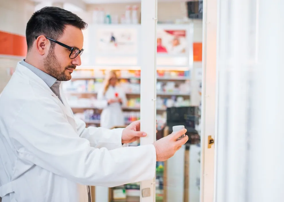 Pharmacist putting medication back on shelf