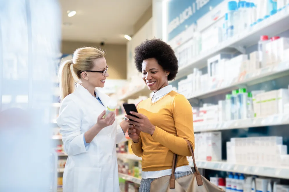 Pharmacist speaking with female customer holding smartphone