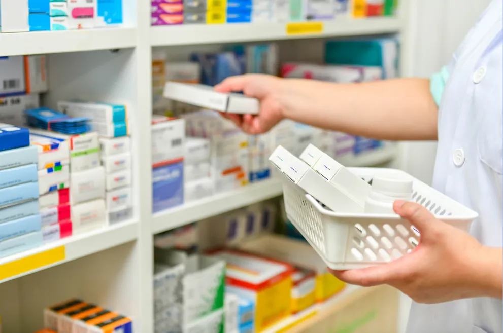 Pharmacist stocking medicine on shelves