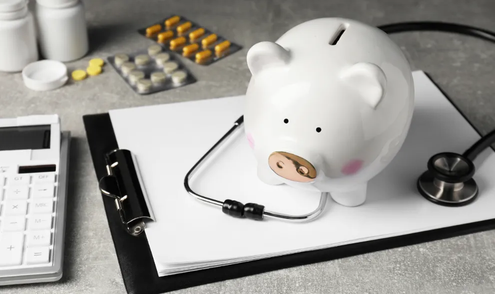 Piggy bank stethoscope calculator clipboard and pills on light grey table