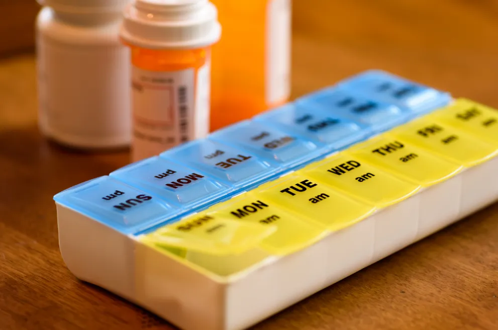 Pill box with pill bottles in background