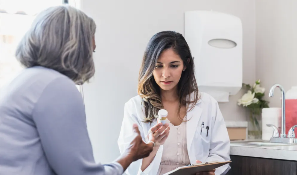 Serious female doctor reads the label on a patient's prescription bottle