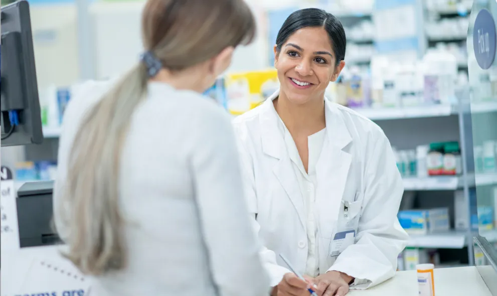 Smiling pharmacist assisting patient