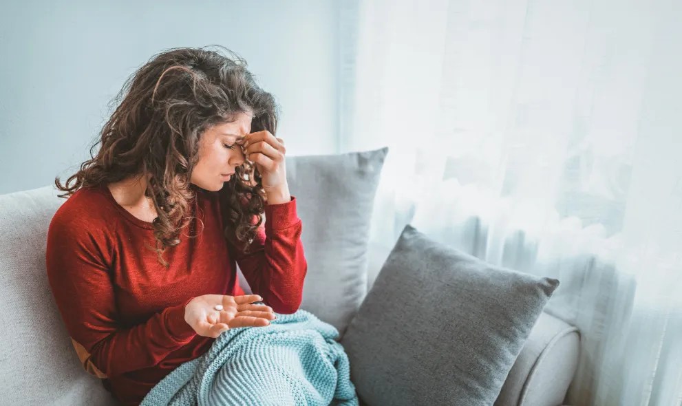 Woman experiencing migraine holding a pill