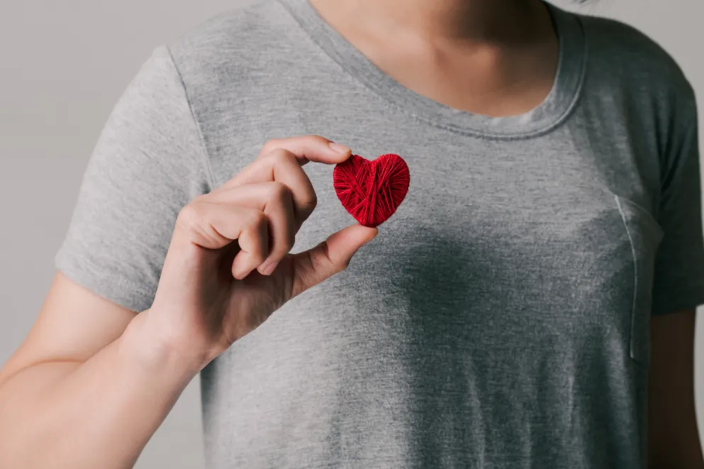 Woman holding red heart made of string