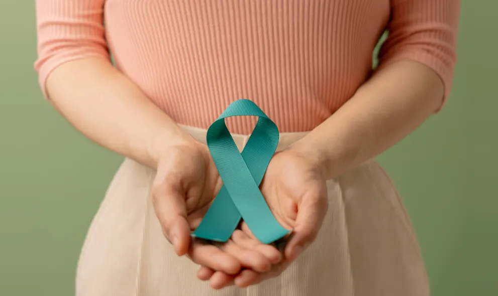 Woman holding teal ribbon on lower abdomen
