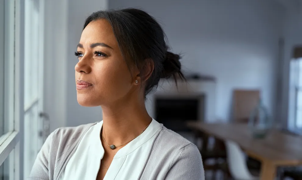 Woman looking outside window with uncertainty