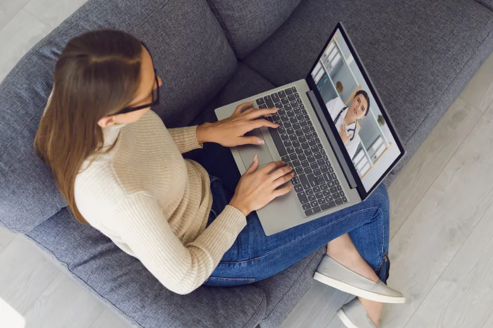 Woman sitting on sofa talking to doctor on laptop