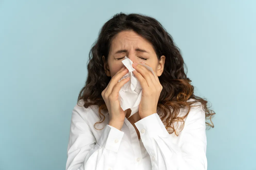 Woman sneezing into tissue